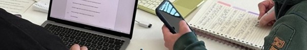 Zwei Weiterbildungsteilnehmende sitzen lernend mit einem Laptop und Büchern an einem Tisch